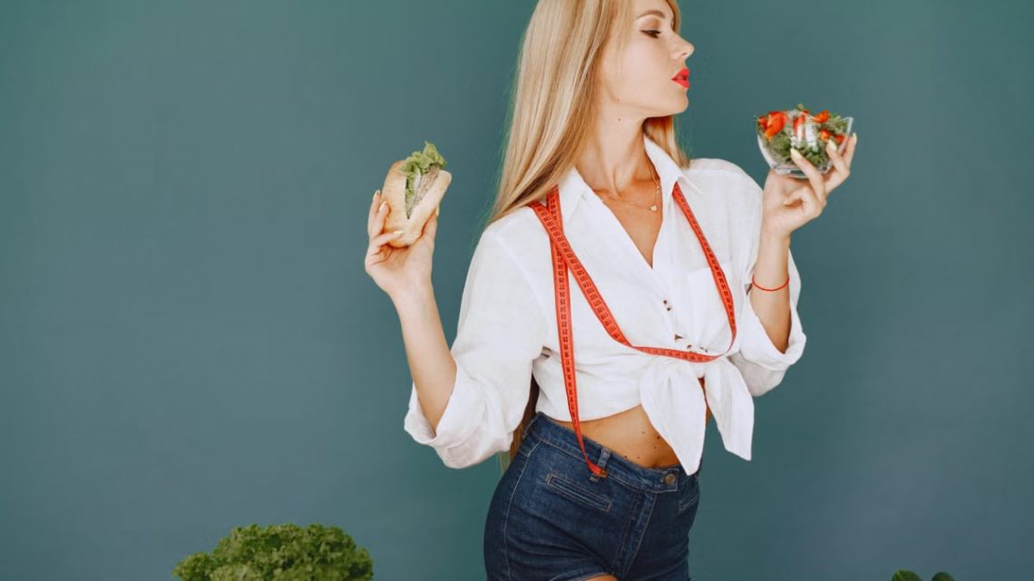 Woman enjoys healthy lifestyle with fresh salad and sandwich, promoting balanced eating.