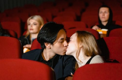 Romantic couple kissing in a cozy movie theater setting.