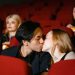Romantic couple kissing in a cozy movie theater setting.